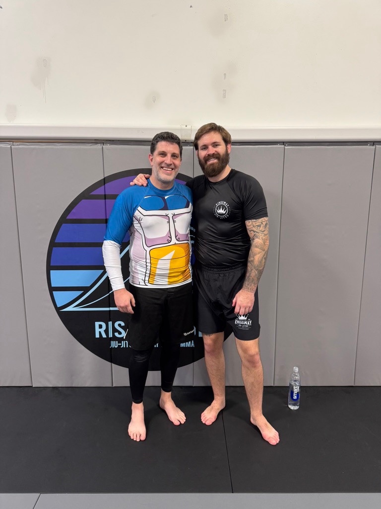 Two people standing together on mats in a martial arts gym