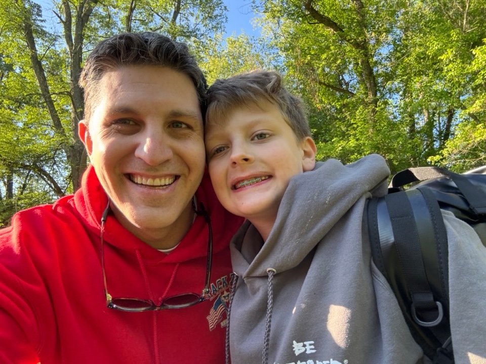 An adult and a child smiling on a wooded path